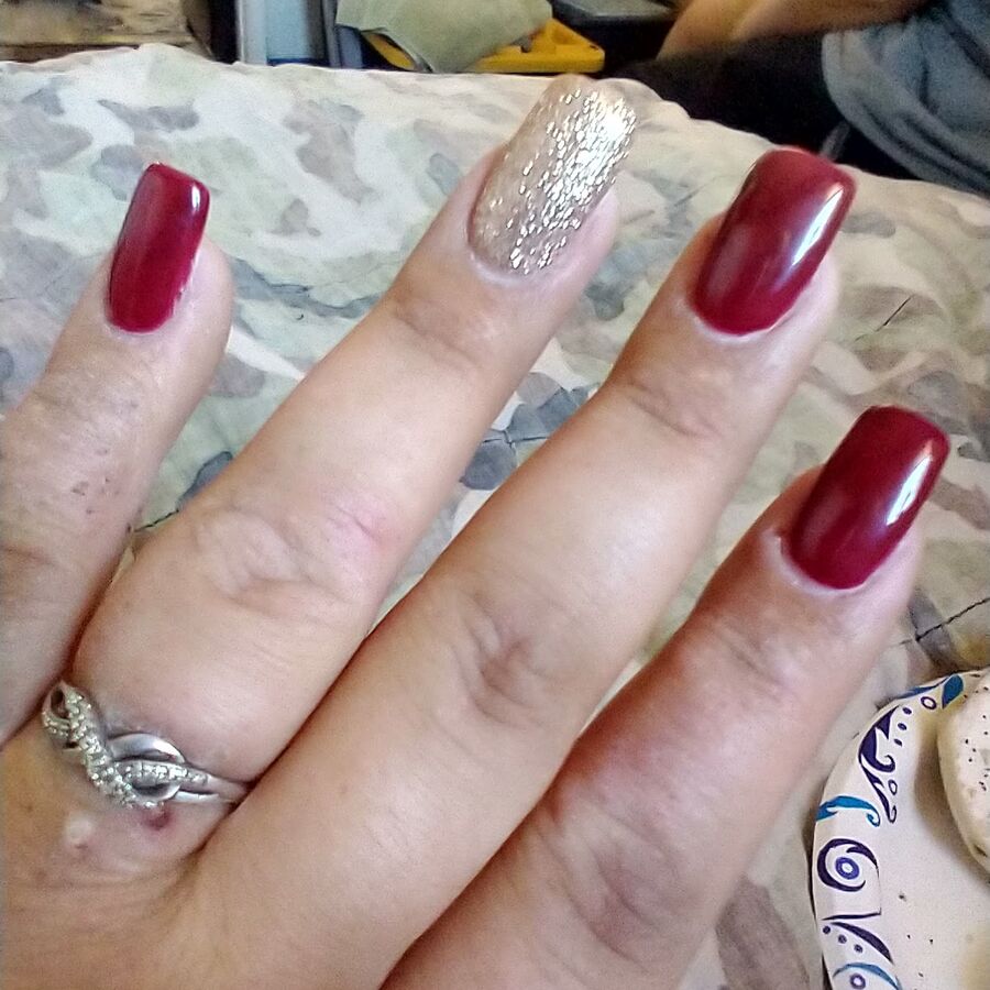 A deep red acrylic set with a gold glitter accent nail, done at Sparkle Pro Nail & Spa in El Cajon